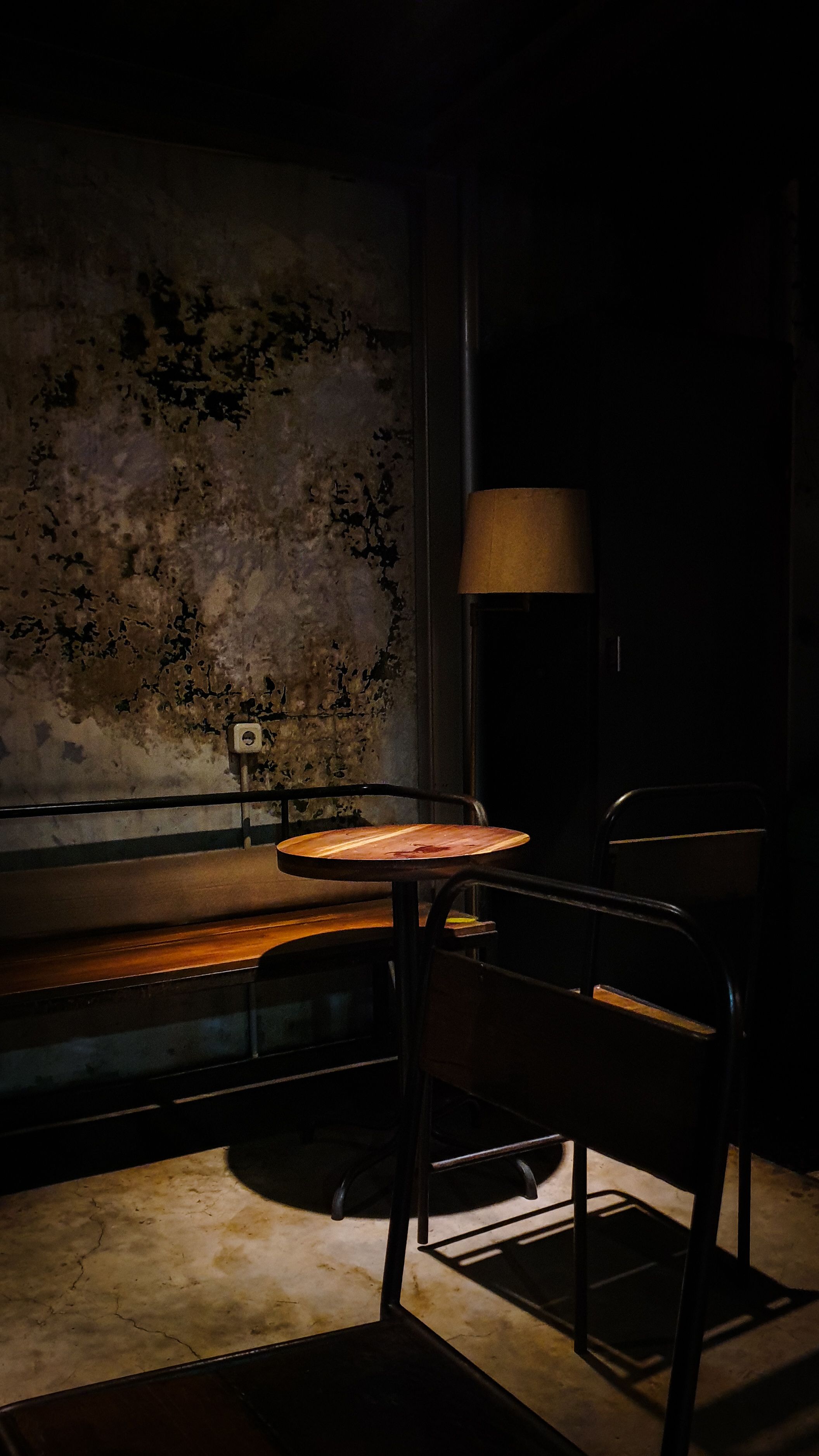 Ruhige Ecke einer Gaststube mit Holzbank, kleinem Tisch und einer Stehlampe im warmen Licht